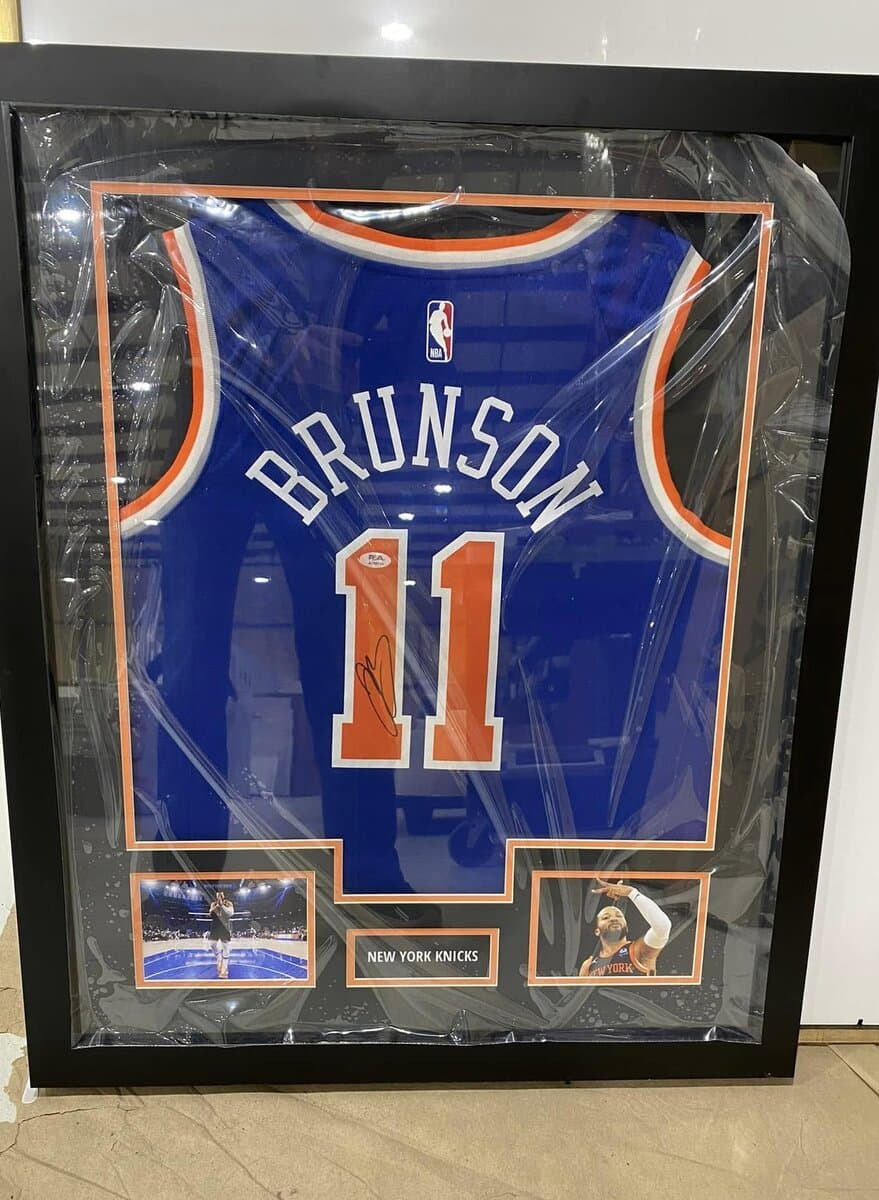 Autographed New York Knicks Jalen Brunson jersey framed for a Manhattan collector with orange and blue matting and action shot