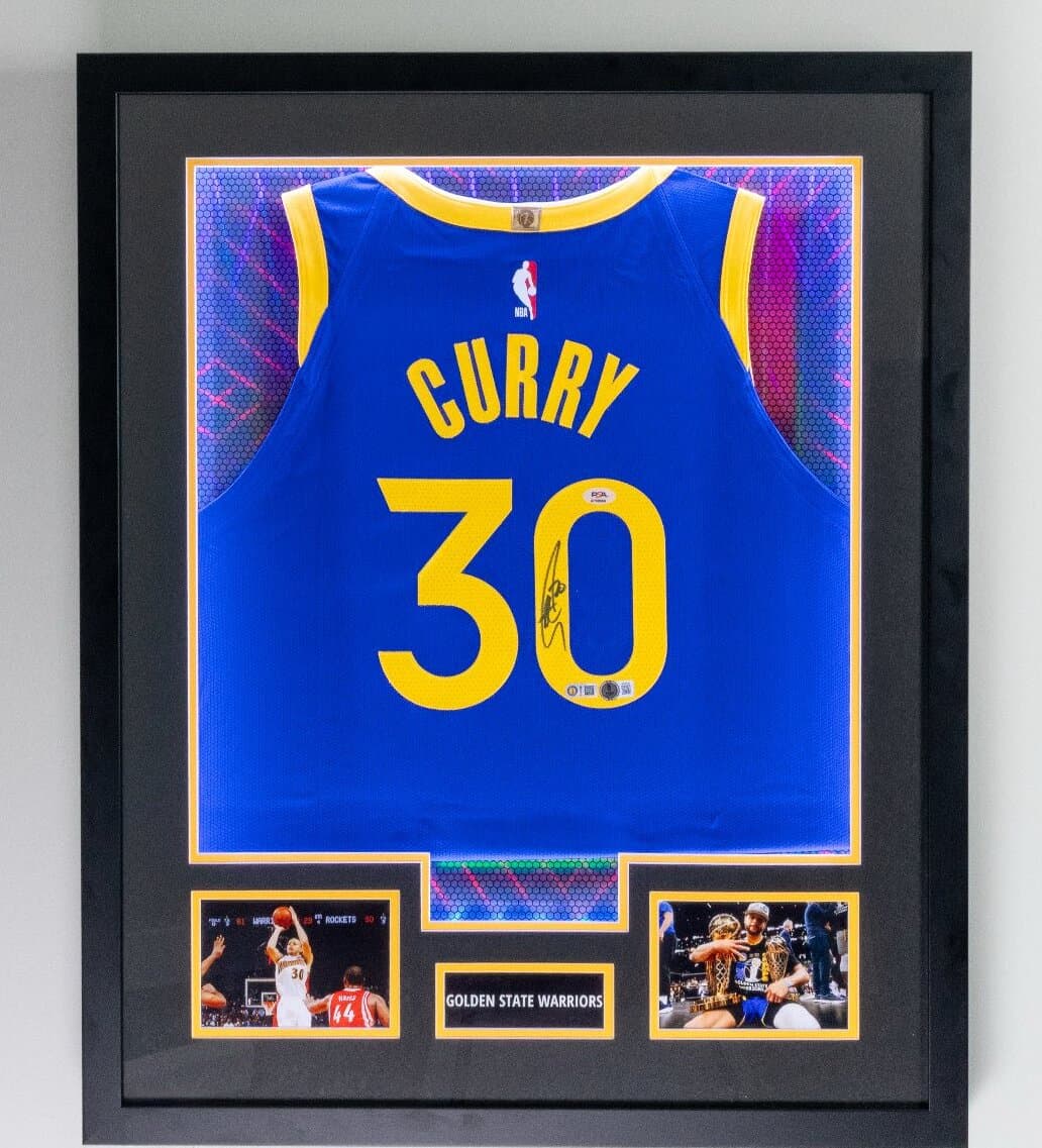 Autographed Stephen Curry Golden State Warriors jersey framed with blue and gold matting and twin action shots