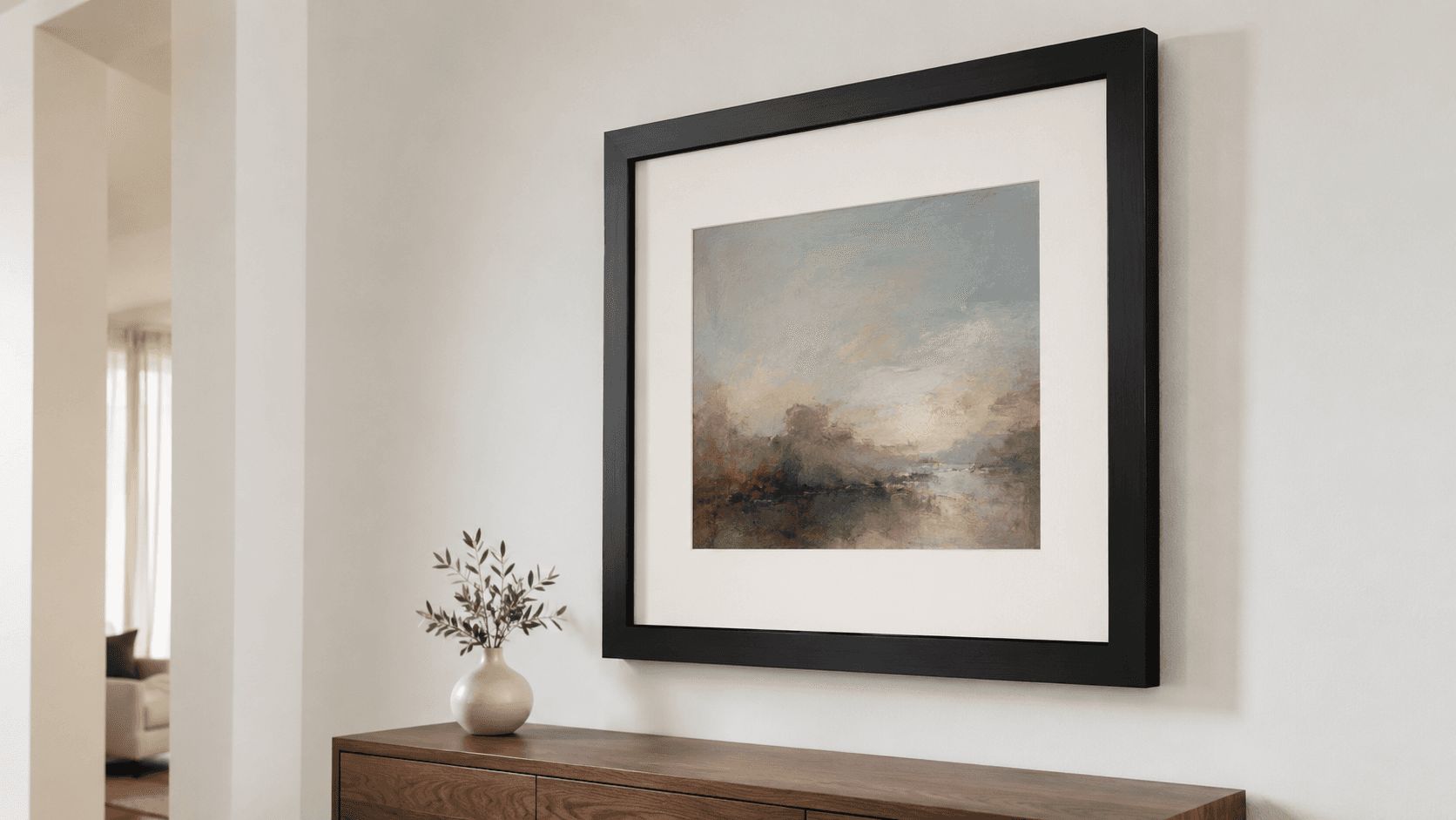 A contemporary atmospheric seascape painting custom framed in a clean black moulding with a wide ivory conservation mat, displayed above a walnut sideboard with a small white vase of olive branches in a sophisticated Princeton-area home
