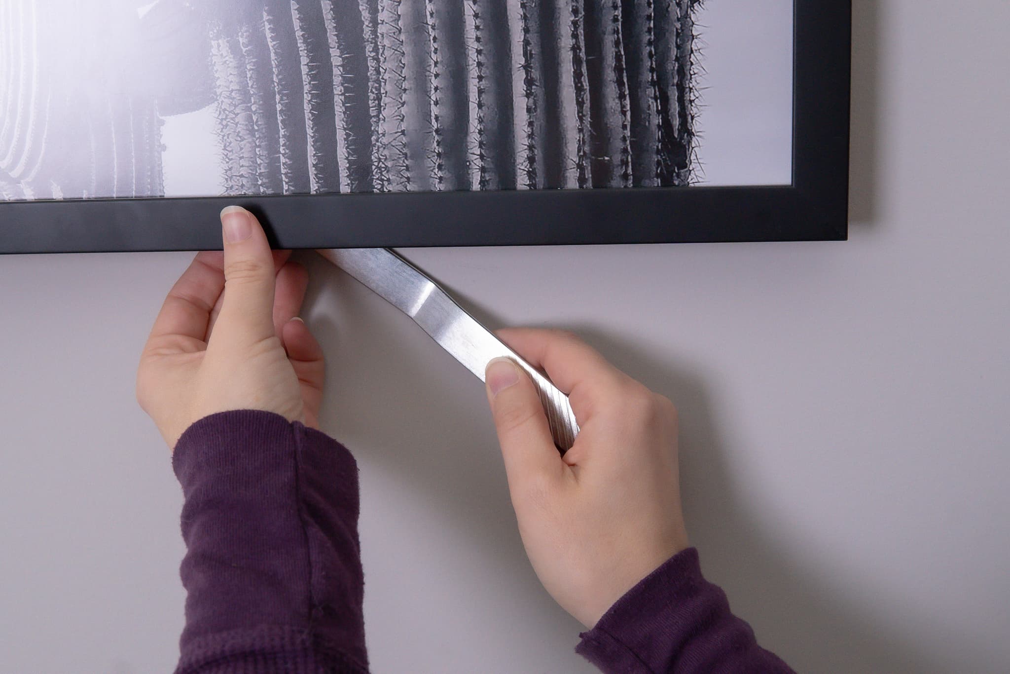 Hand installing anti-theft security bracket with T-screw lock system on picture frame back