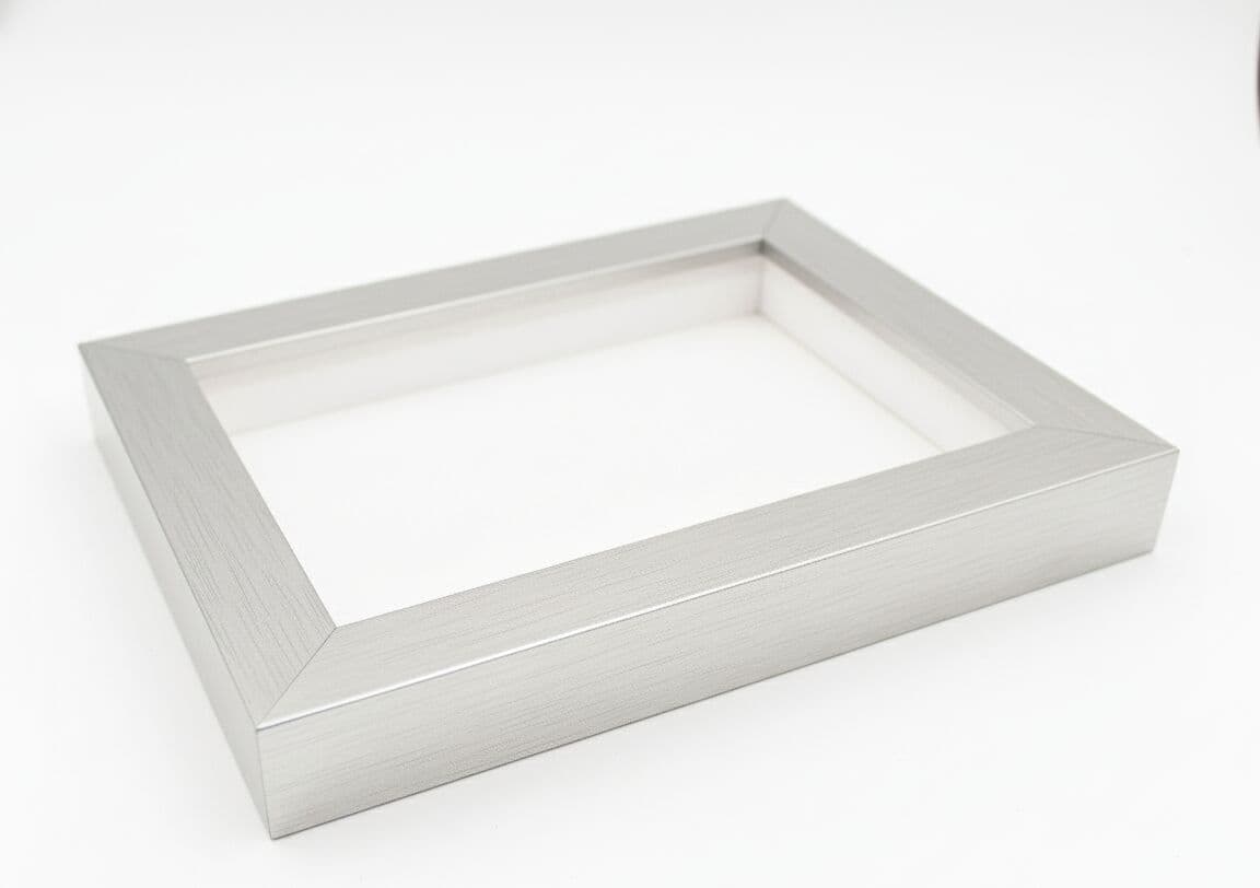 Professional product photography of empty brushed silver shadowbox frame on white background showing clean modern design 1 inch moulding width and 1.5 inch depth capacity demonstrating quality deep picture frame construction for custom dimensional framing