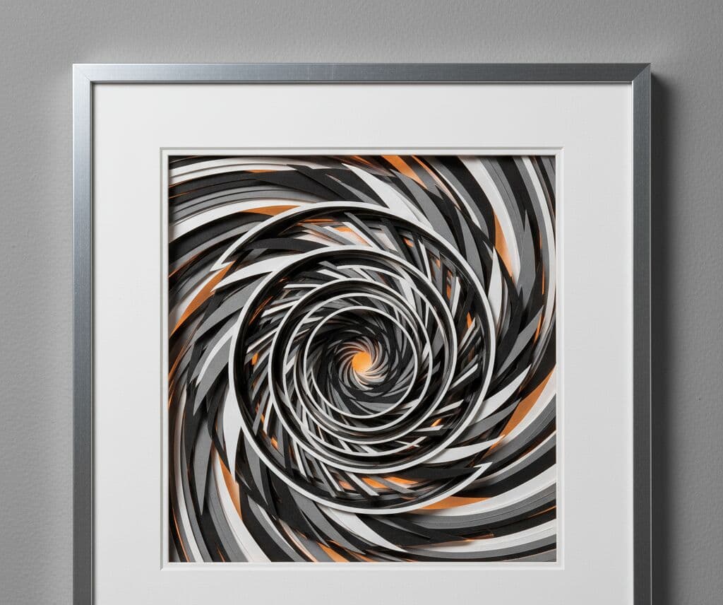 Brushed silver picture frame with white mat board displaying abstract spiral paper cut artwork in black white gray and copper tones on gray background demonstrating contemporary shadowbox frame for modern geometric art layered paper design and dimensional wall art