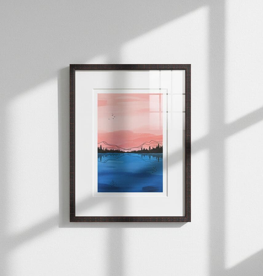 Dark wood picture frame with white mat displays minimalist landscape painting in pink and blue hues against white wall with sunlight