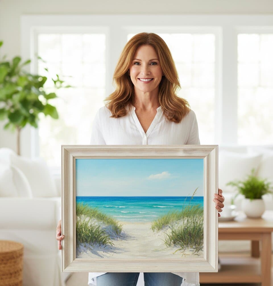 Woman holds Coastal Picture Frame with double white mat showcasing beach dunes seascape painting featuring sea oats sandy beach path turquoise ocean and clear blue sky a strong choice for coastal home decor in whitewashed 1.75 inch wood picture frame