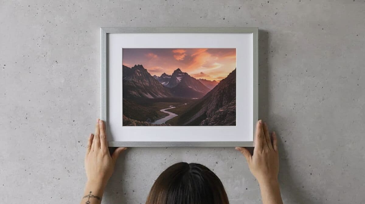 Woman hanging Silver Picture frame displaying dramatic mountain sunset landscape photography showcasing sleek metallic finish for nature photography