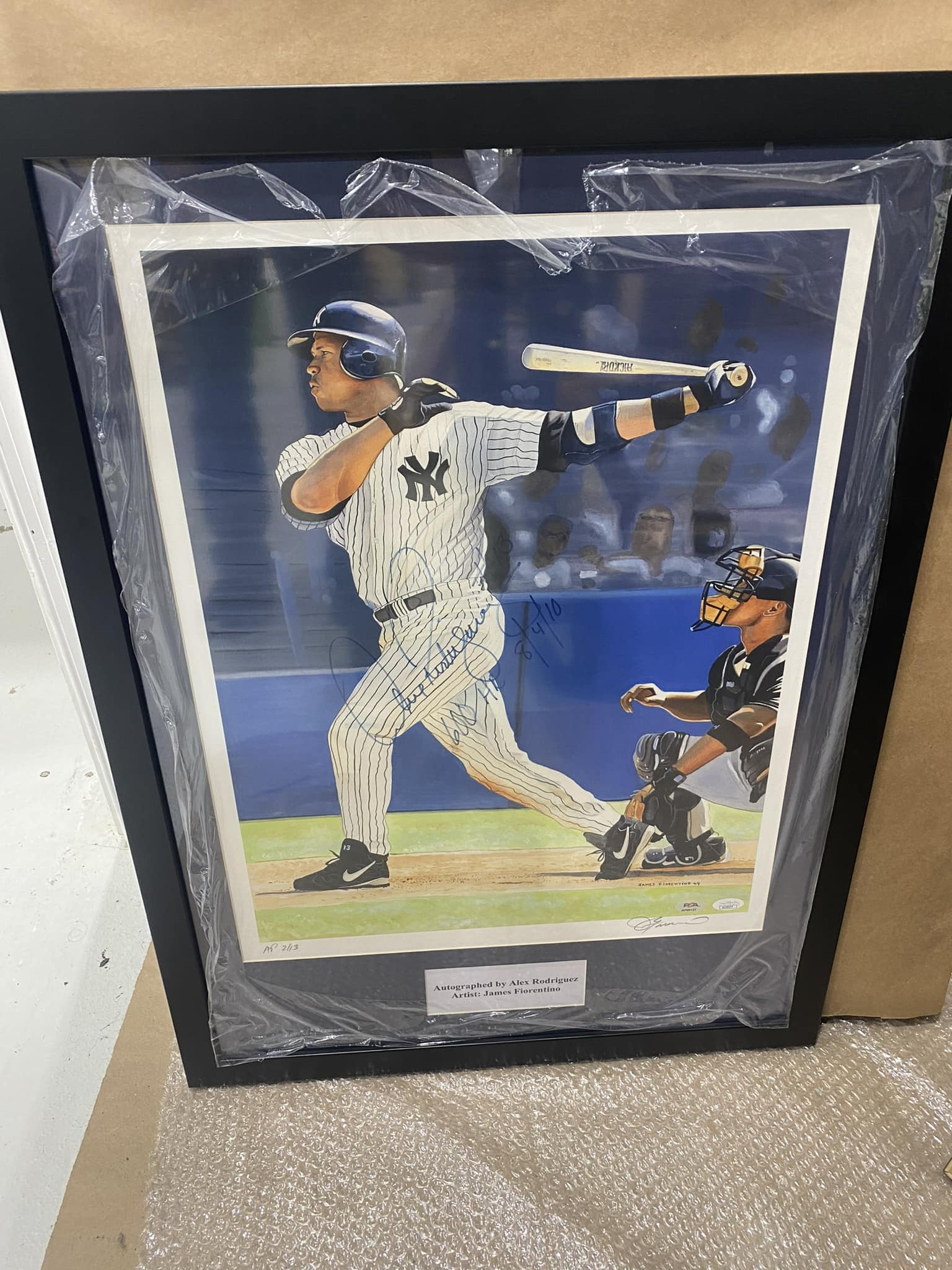 Signed Alex Rodriguez batting print by artist James Fiorentino (A-Rod follow-through swing with catcher in foreground) framed in a black moulding with PSA authentication and 'Autographed by Alex Rodriguez' nameplate
