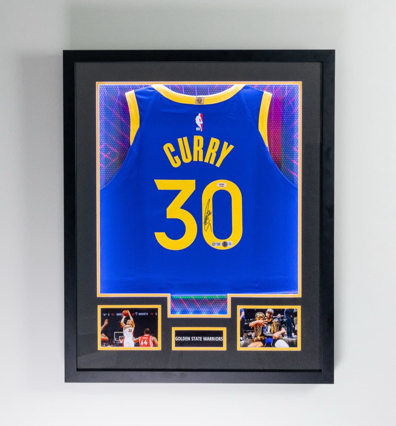 Autographed Stephen Curry Golden State Warriors #30 jersey framed in a shadow box with team patterned matting, twin action photos, and 'Golden State Warriors' nameplate