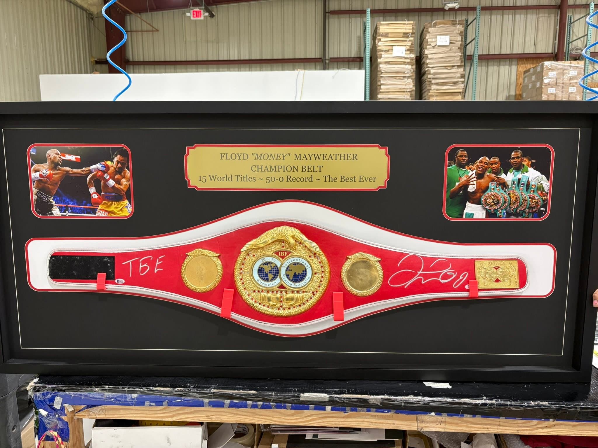 Signed Floyd 'Money' Mayweather IBF World Champion red and gold belt framed in a wide black shadow box with twin ring-action shots and engraved 'Floyd Money Mayweather Champion Belt - 15 World Titles - 50-0 Record - The Best Ever' tribute plate