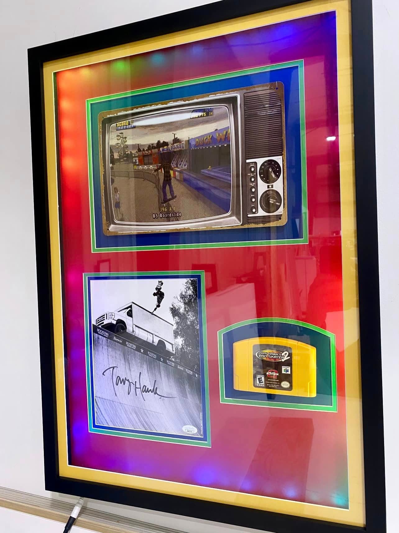 Tony Hawk's Pro Skater 2 themed skateboard deck framed vertically inside a black shadow box with branded backing artwork