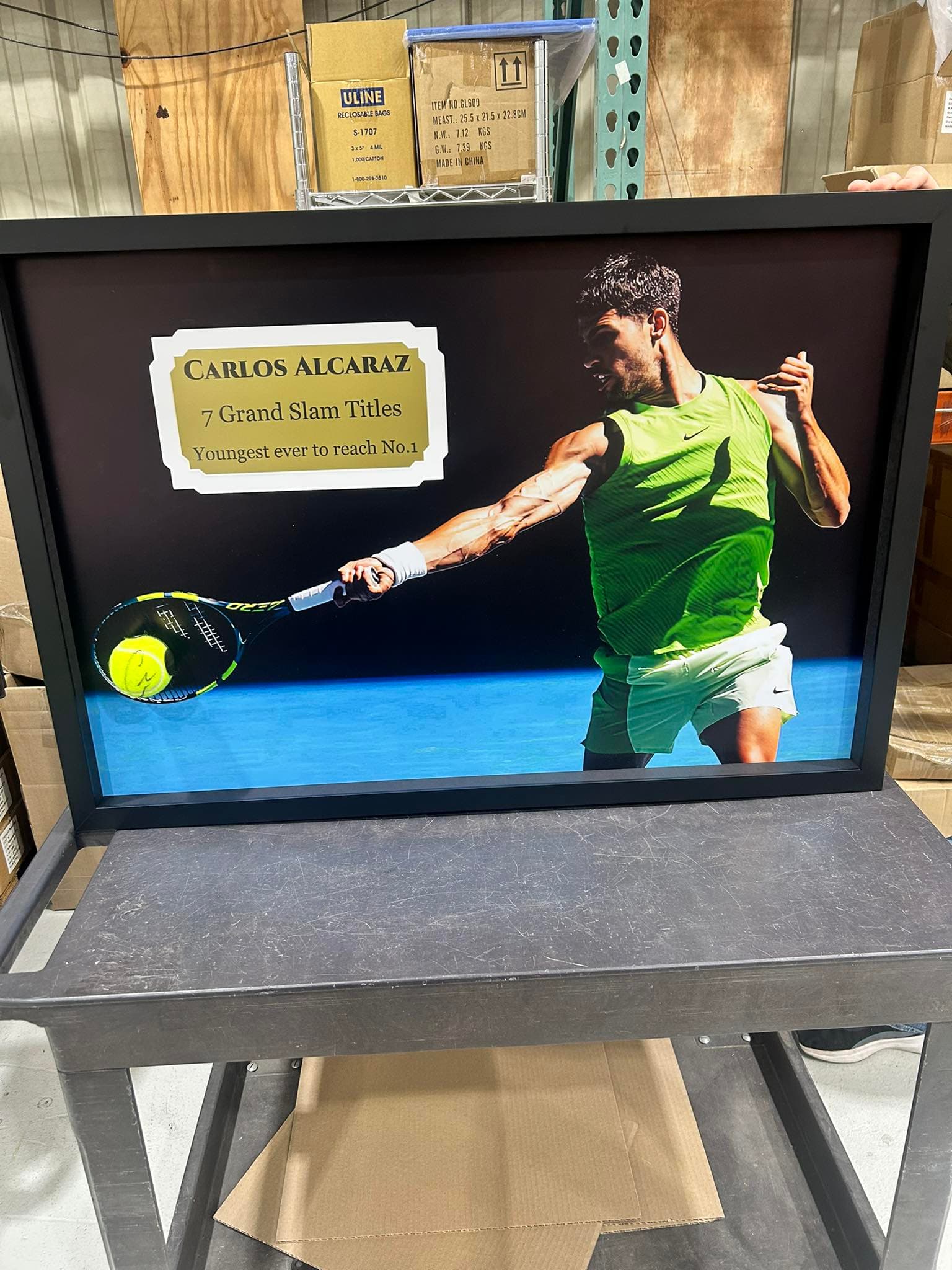 Carlos Alcaraz forehand action shot framed in a black moulding with a gold engraved nameplate reading 'Carlos Alcaraz - 7 Grand Slam Titles - Youngest ever to reach No.1'