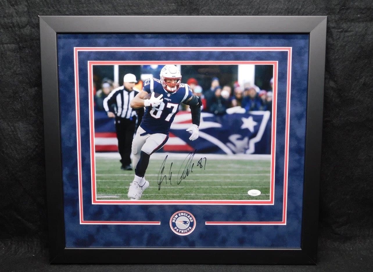 JSA-authenticated signed Rob Gronkowski New England Patriots #87 action shot framed in a black moulding with a navy suede double mat trimmed in red and an embroidered Patriots logo patch