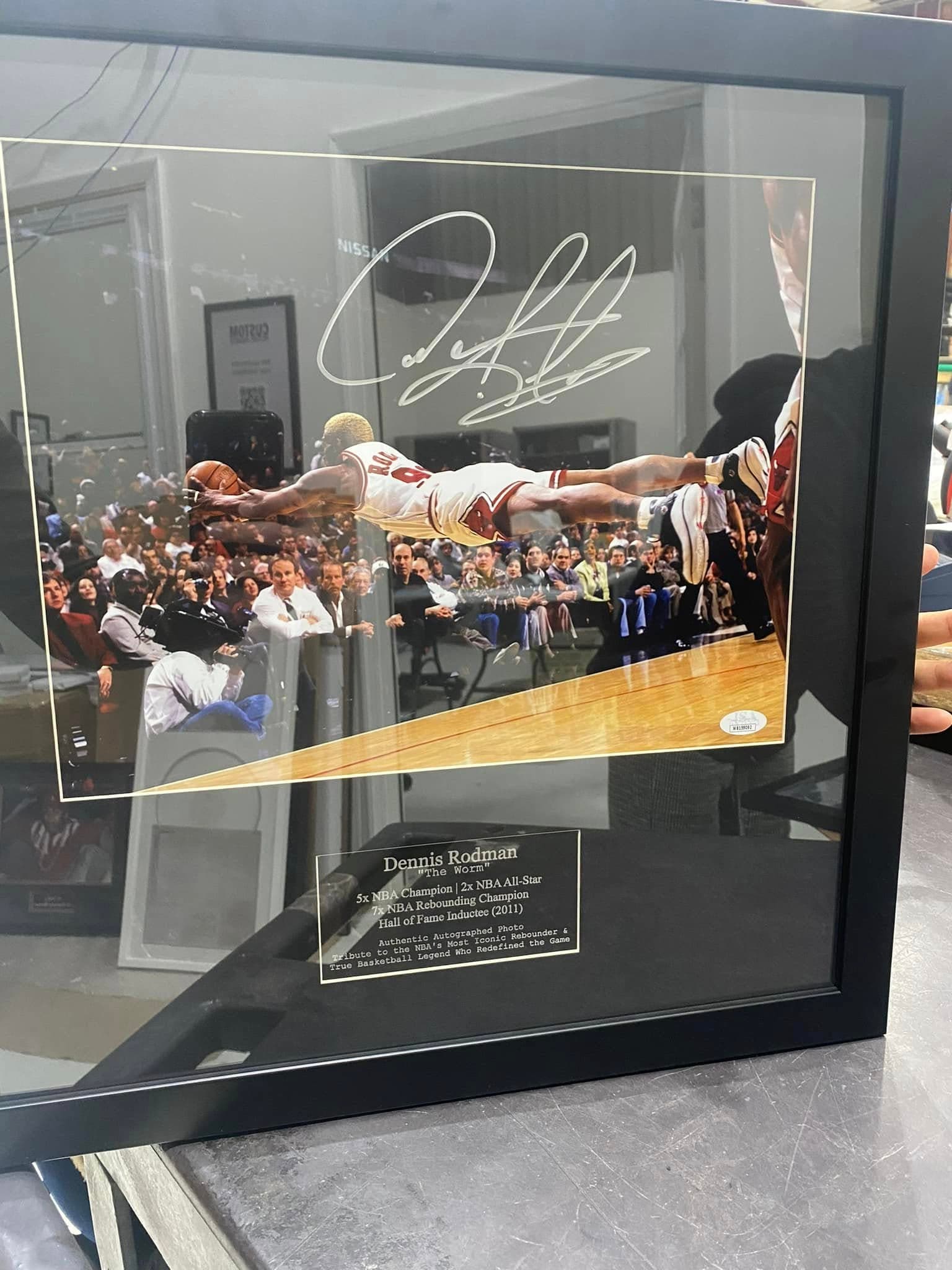JSA-authenticated signed Dennis Rodman Chicago Bulls courtside dive action shot framed in a black moulding with a black mat and an engraved 'Dennis Rodman - The Worm' tribute nameplate listing 5x NBA Champion, 2x NBA All-Star, 7x NBA Rebounding Champion, Hall of Fame inductee (2011)