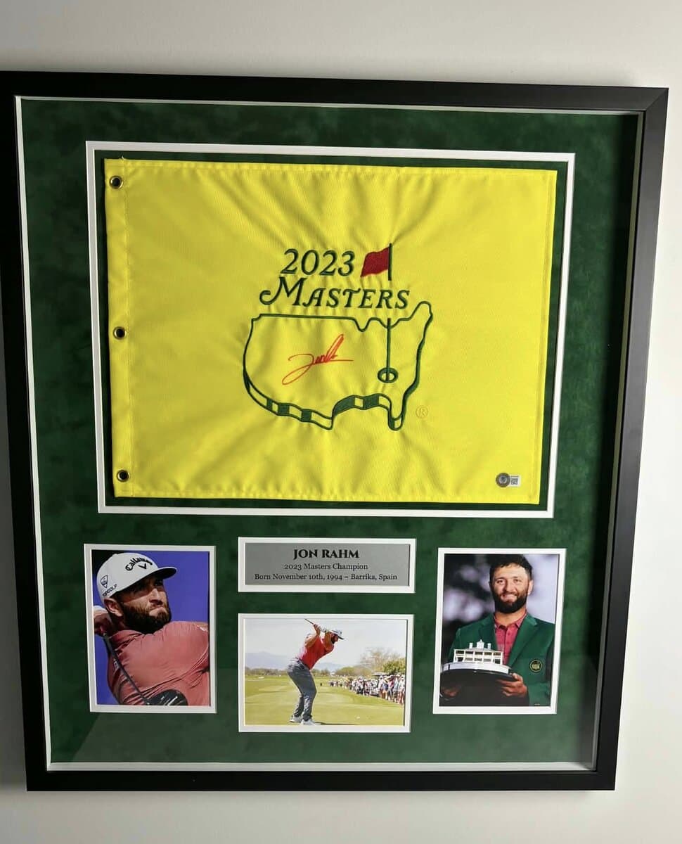 Shadow box framing example: Jon Rahm 2023 Masters pin flag in green suede shadow box with Champion nameplate